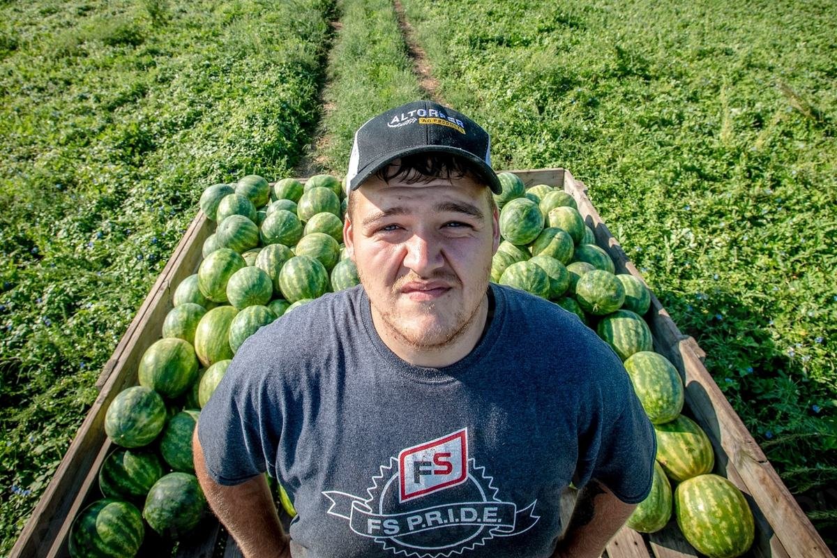 Produtor rural ao lado de uma carreta cheia de melancias